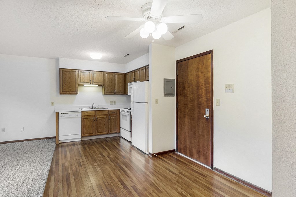 an empty kitchen with white appliances and wood flooring