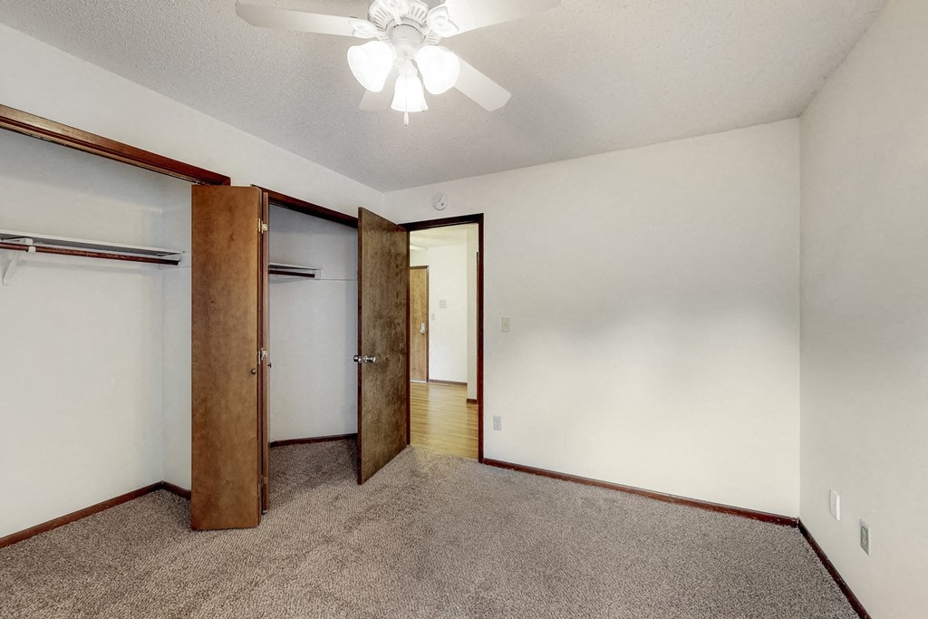 an empty room with a closet and a ceiling fan