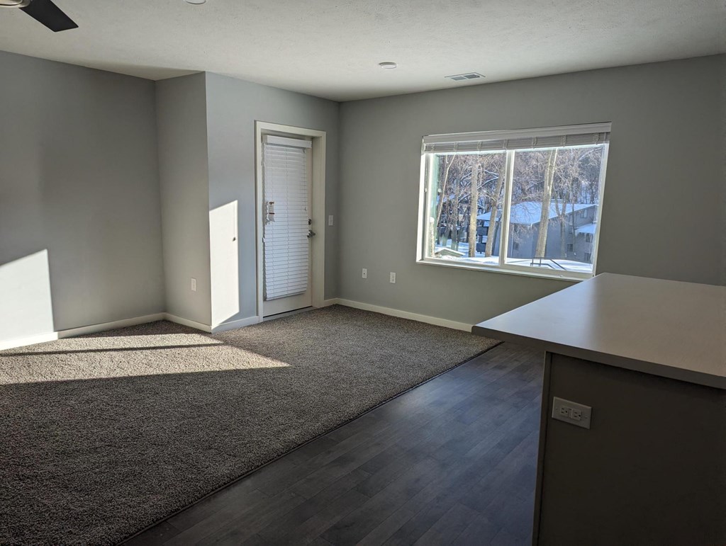 an empty living room with gray walls and a window