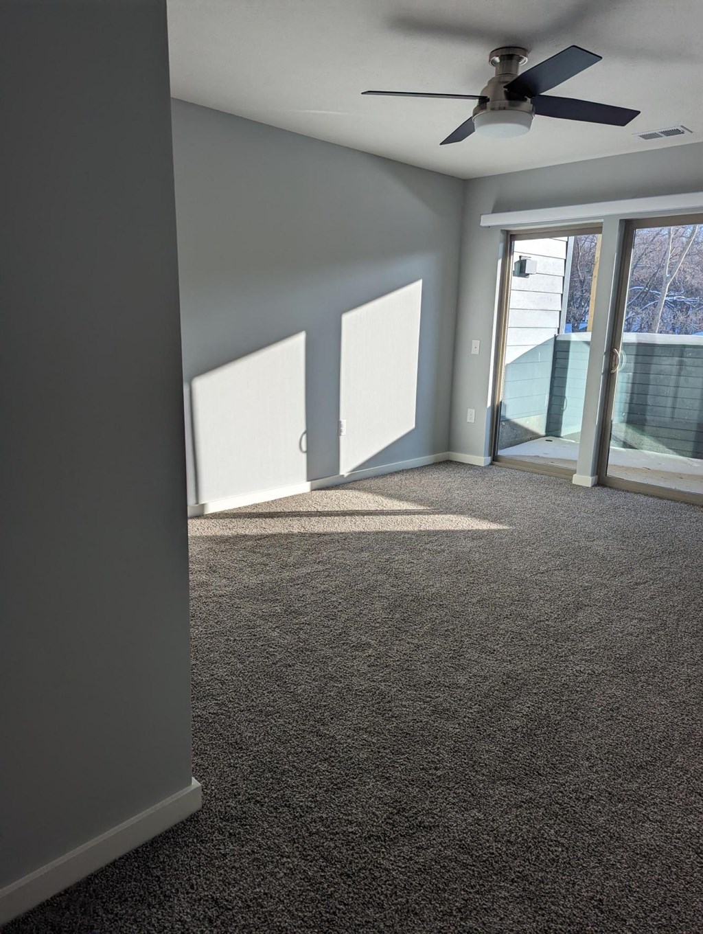 an empty living room with a ceiling fan and a window