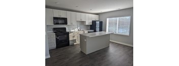 a kitchen with white cabinets and black appliances and a white counter top