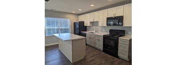 a kitchen with white cabinets and black appliances