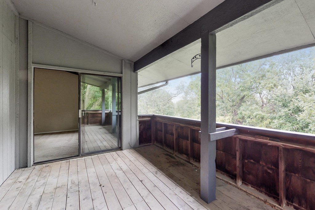 the deck has a view of the woods and a large sliding glass door