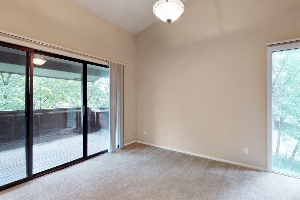 an empty living room with sliding glass doors to a deck