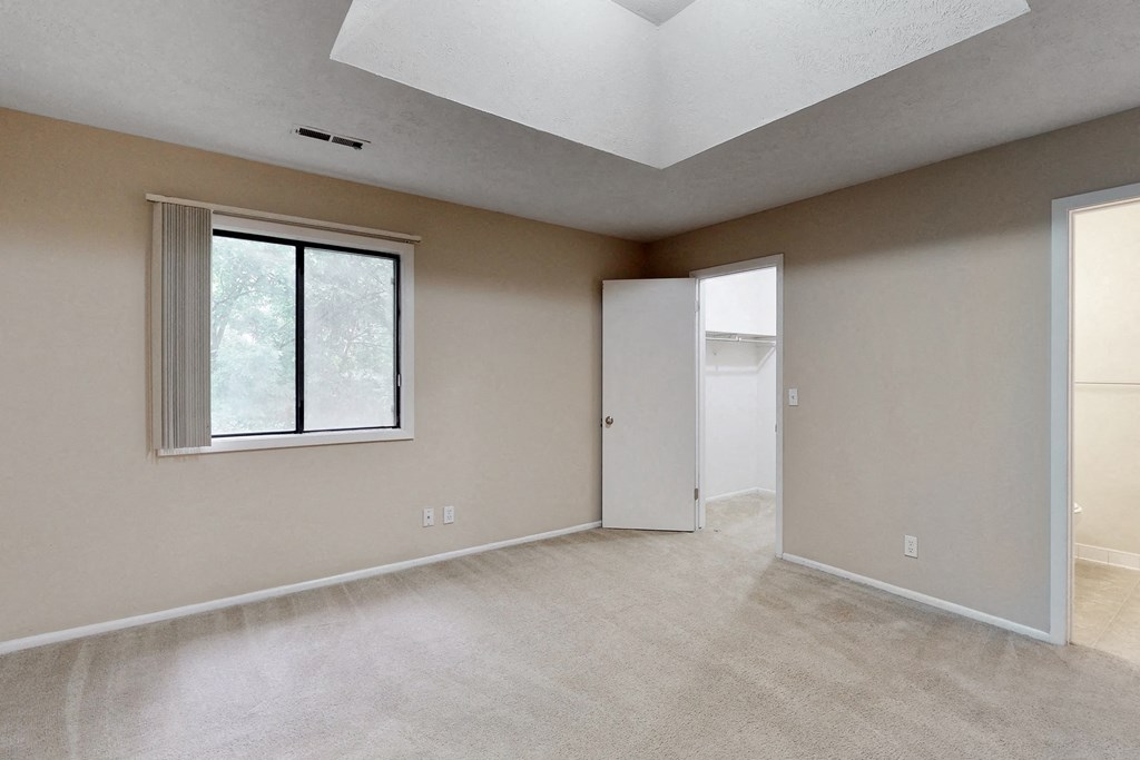 the spacious living room of an empty home with a large window