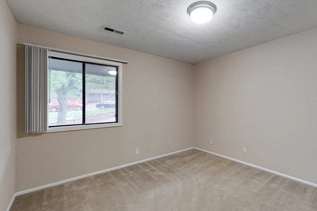 an empty living room with a large window and carpeting