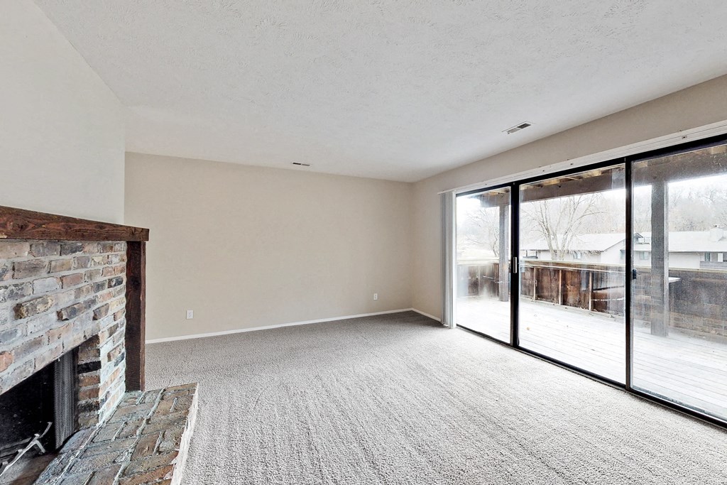 an empty living room with a fireplace and sliding glass doors