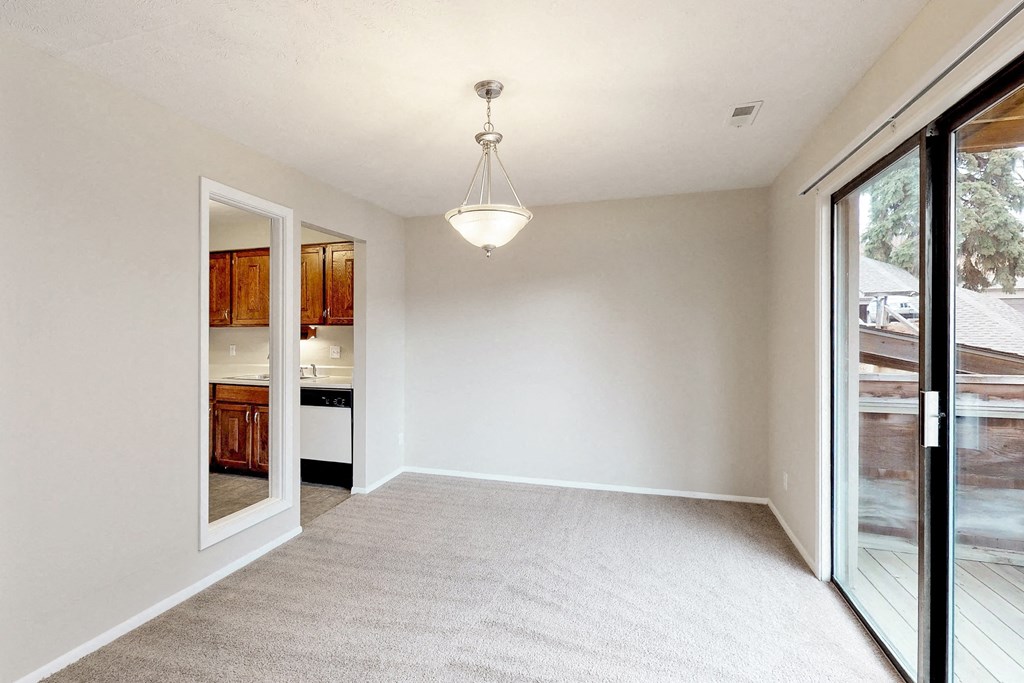 an empty living room with sliding glass doors to a kitchen
