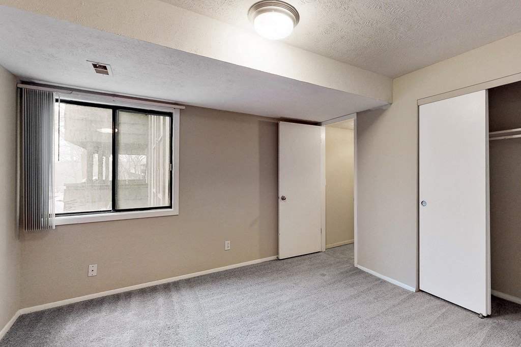 an empty living room with a window and a closet