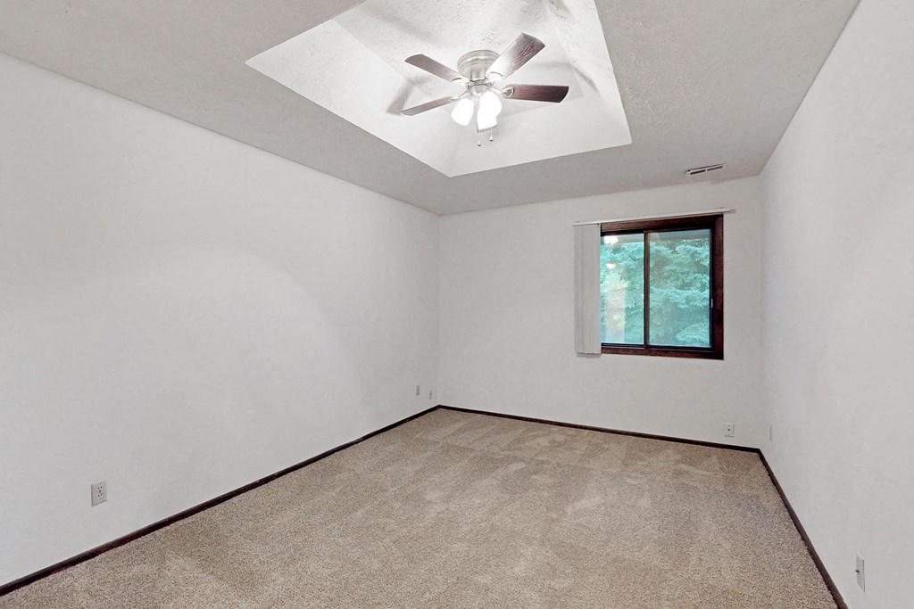 an empty room with a ceiling fan and a window
