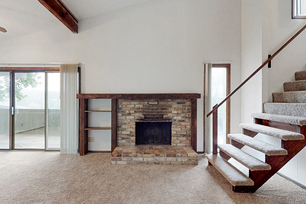a large living room with a stone fireplace and stairs