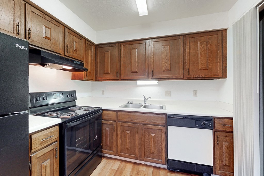 an empty kitchen with black appliances and wooden cabinets