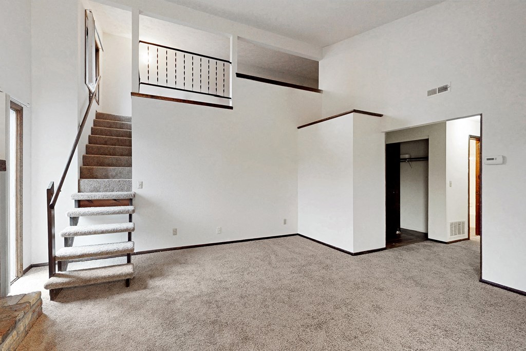 an empty living room with a staircase and white walls