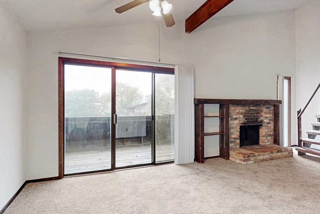 an empty living room with a fireplace and sliding glass doors