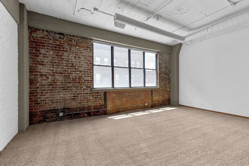 an empty room with a brick wall and a large window