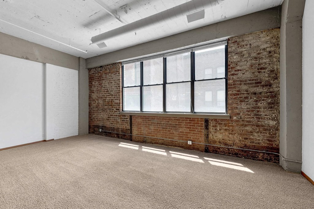 an empty room with a brick wall and a large window