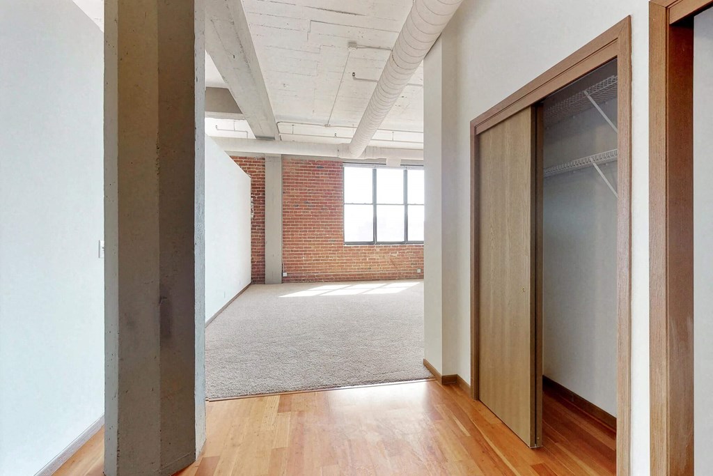 an empty room with an open door and a brick wall