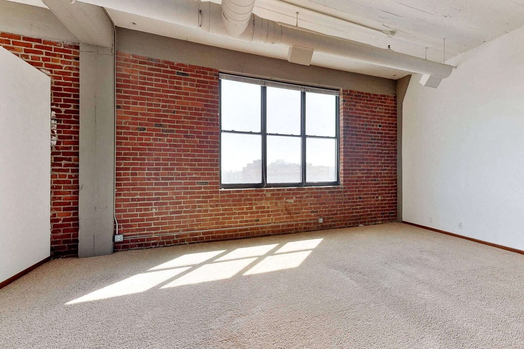 an empty room with a brick wall and a window