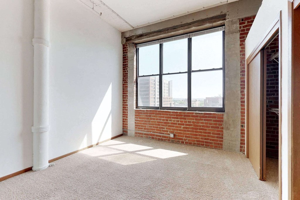 an empty room with a brick wall and a large window