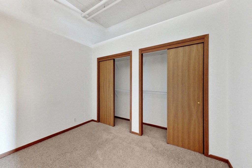 a bedroom with two closets and a carpeted floor