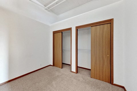 a bedroom with two closets and a carpeted floor