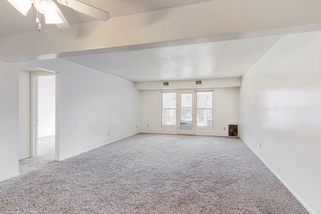 an empty living room with white walls and carpet