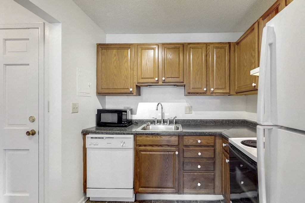 an empty kitchen with wooden cabinets and white appliances