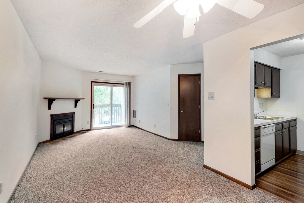an empty living room with a fireplace and a kitchen