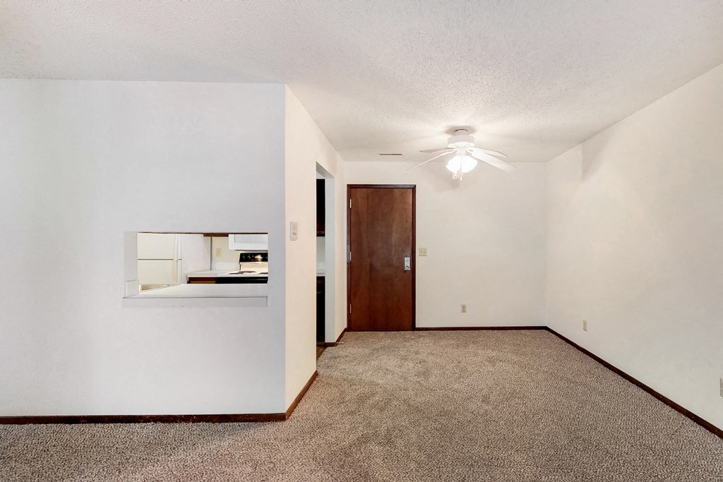 an empty living room with carpet and a ceiling fan