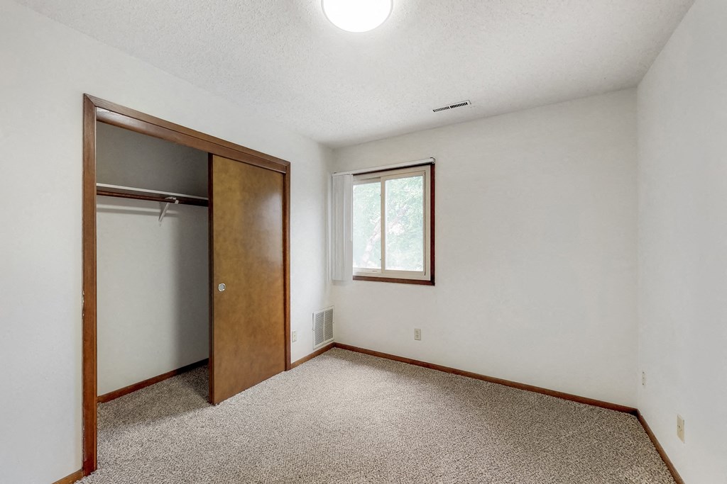 an empty bedroom with a closet and a window