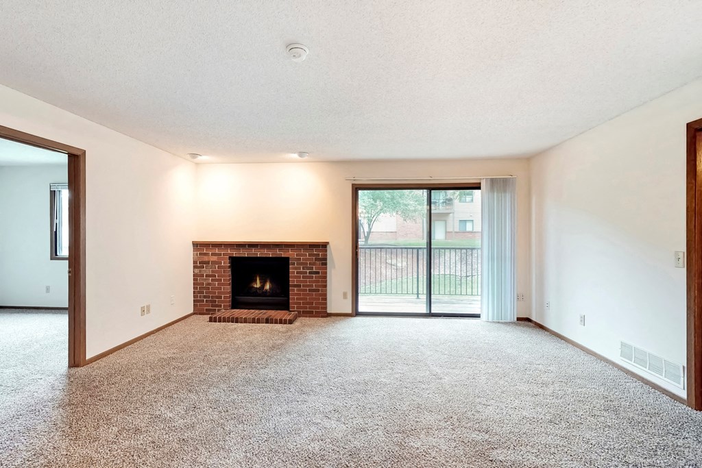 an empty living room with a fireplace and a sliding glass door