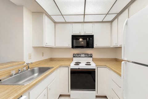 an empty kitchen with white cabinets and a stove and microwave