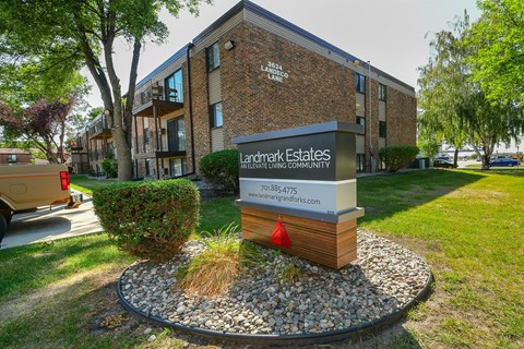 A sign for Landmark Estates is in front of a brick building.