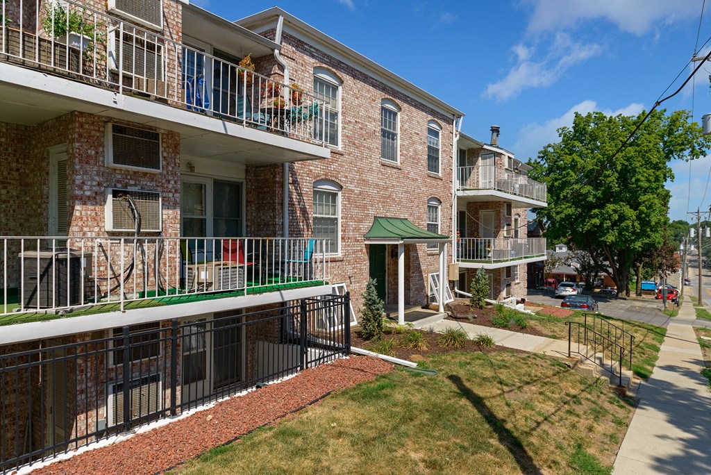 a brick apartment building with balconies and grass and trees