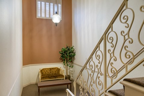 a living room with a gold couch and a staircase
