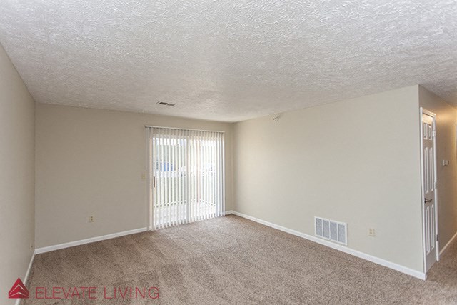an empty living room with a door to a balcony
