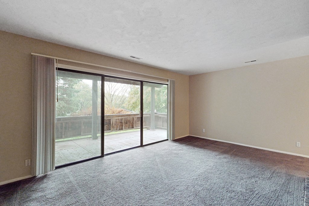 an empty living room with sliding glass doors to a balcony