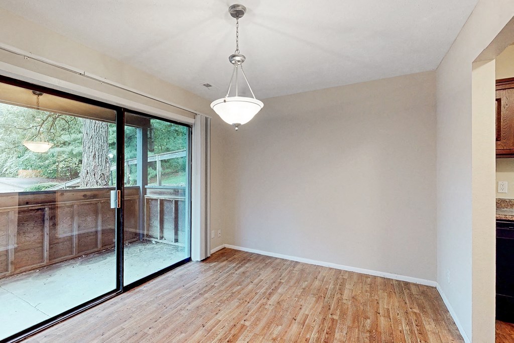 an empty living room with a sliding glass door to a deck
