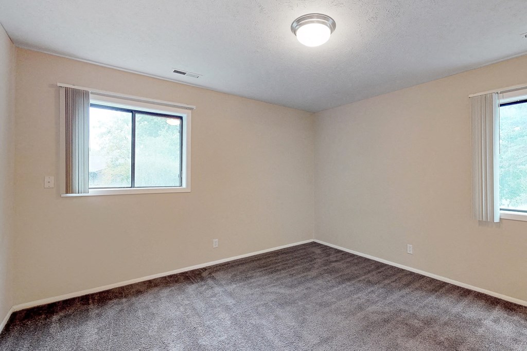 an empty bedroom with carpet and a window