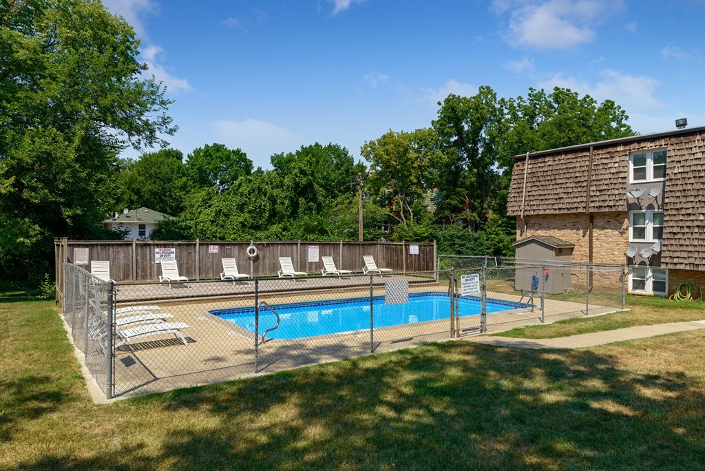 a swimming pool in front of a house with a fence around it