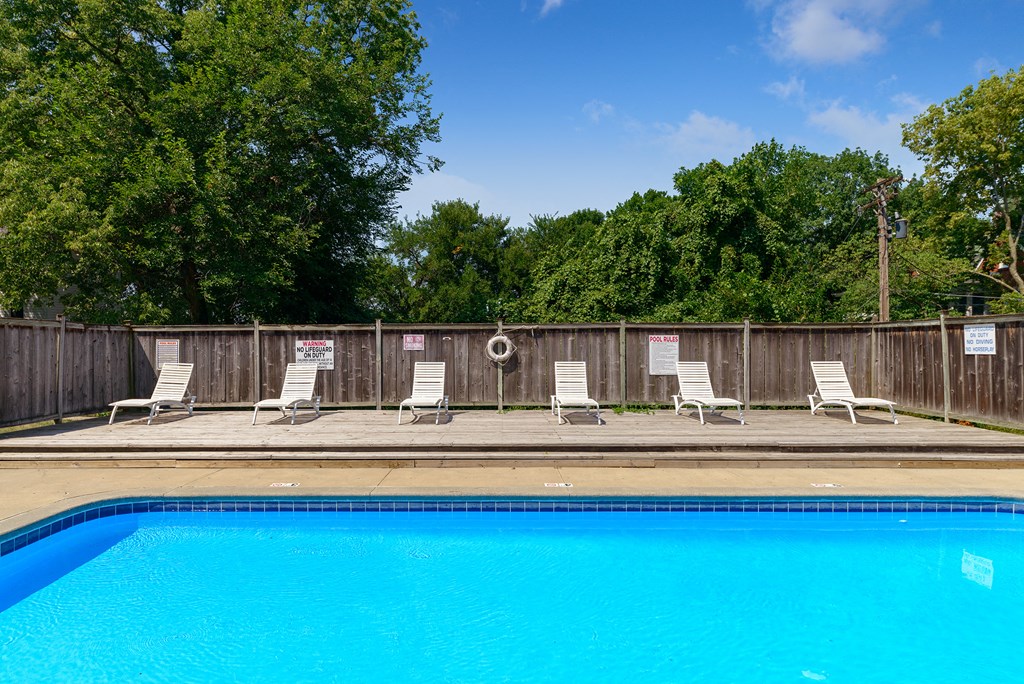 a swimming pool with white chairs and a blue pool