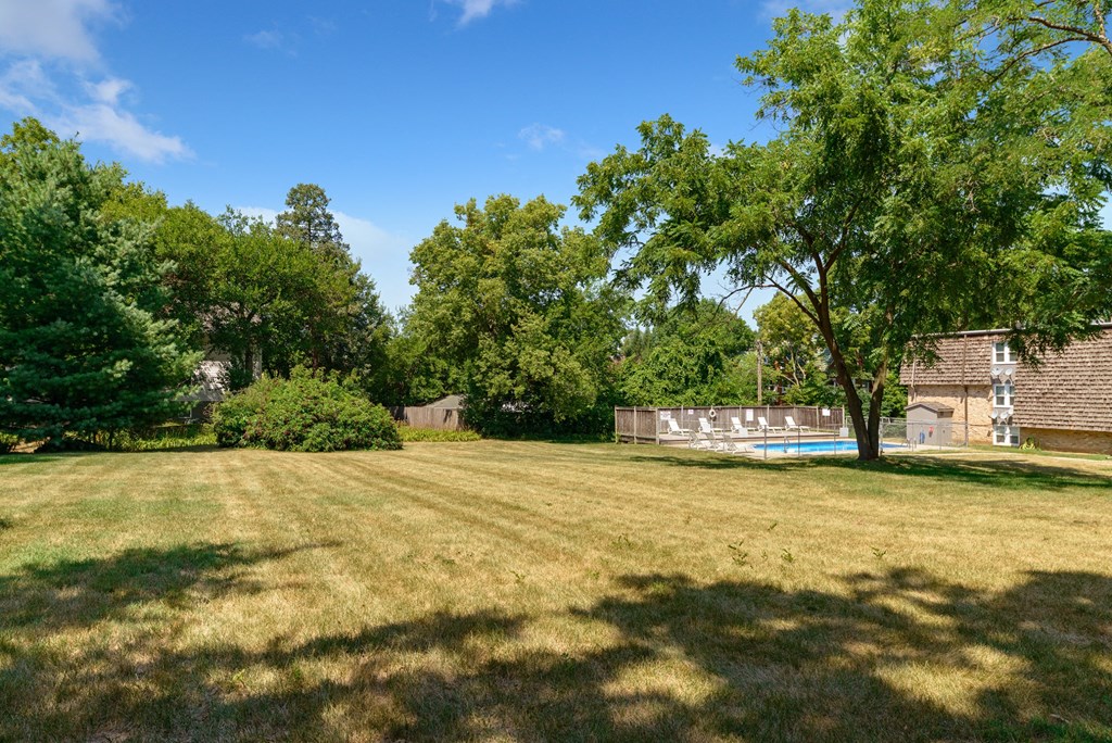 a large yard with a pool and a house in the background
