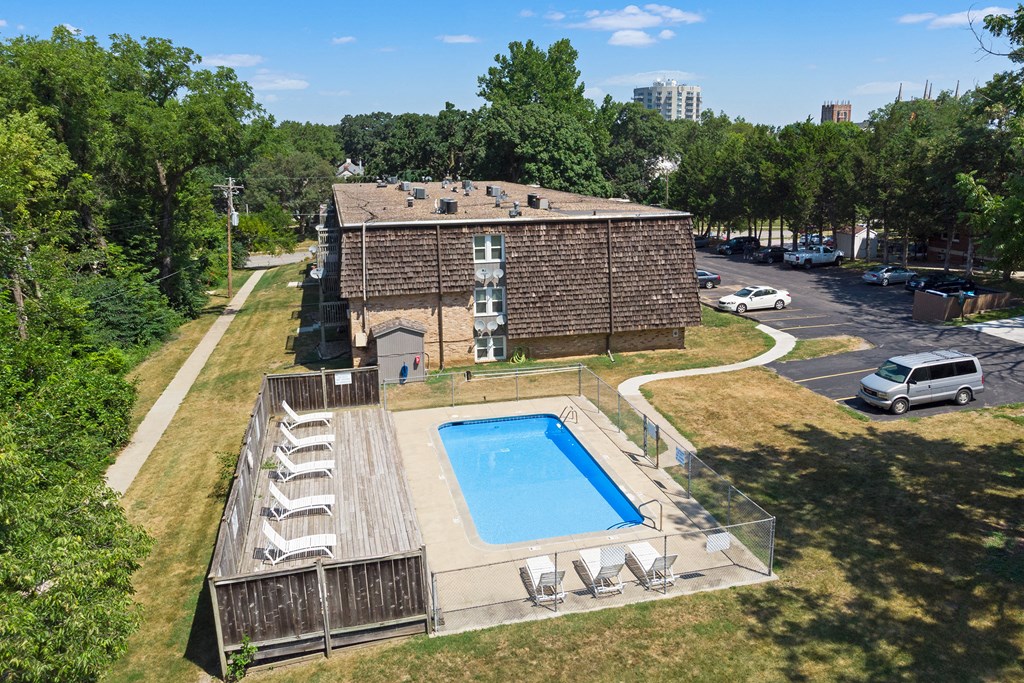 an aerial view of a pool in front of a brick building