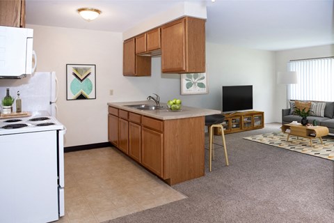 A kitchen with a white stove top oven and wooden cabinets.