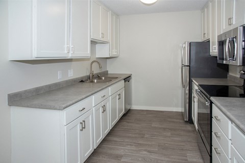 A kitchen with white cabinets and a grey countertop.