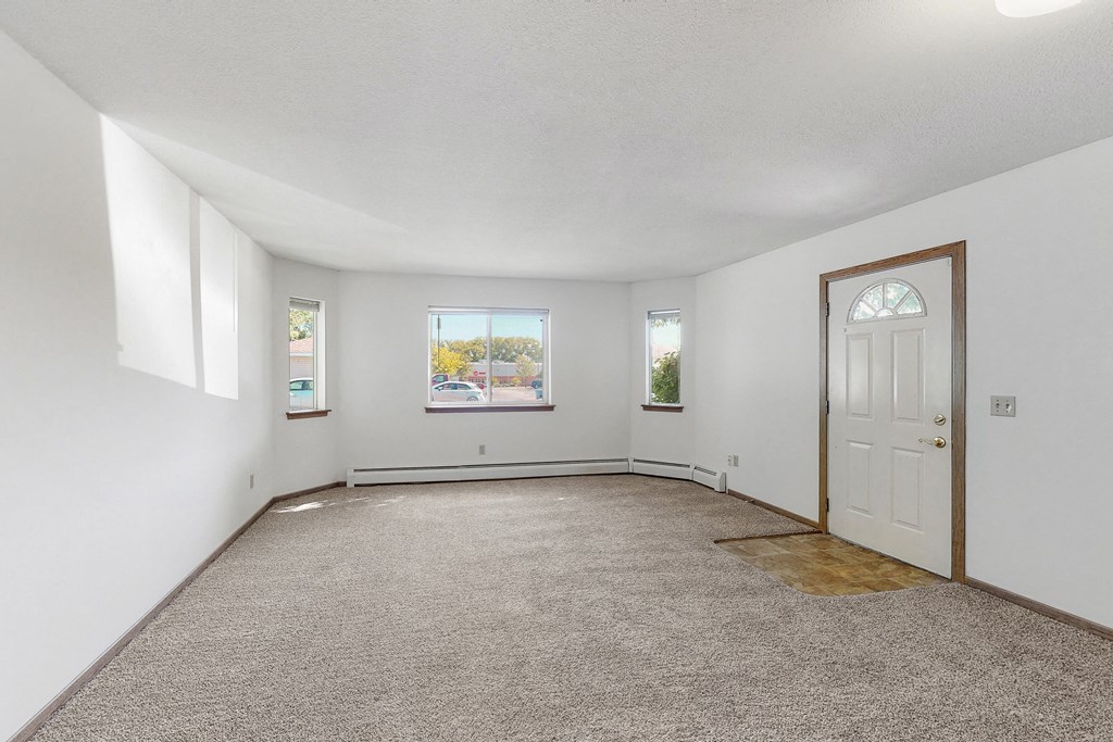 an empty living room with a white door and carpet
