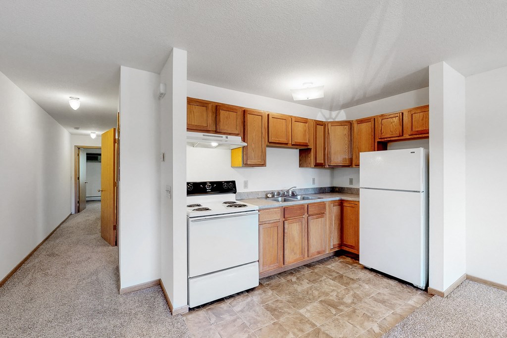 an empty kitchen with white appliances and wooden cabinets