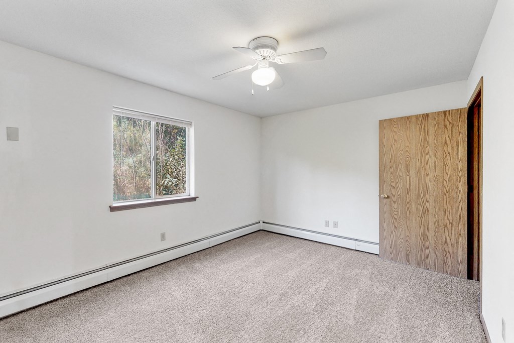 an empty bedroom with a ceiling fan and a window