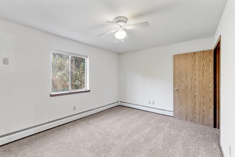 an empty bedroom with a ceiling fan and a window