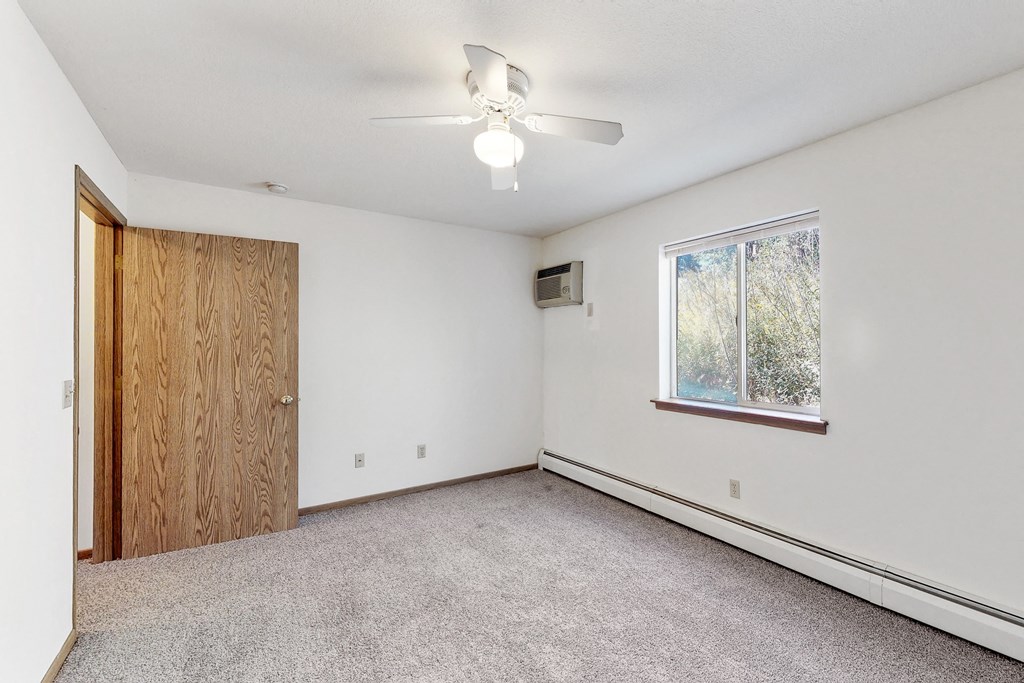 an empty living room with a ceiling fan and a window